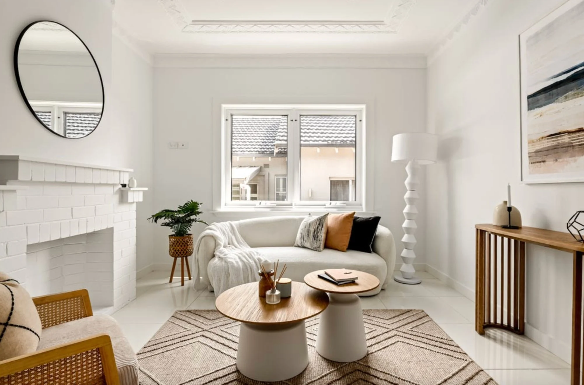 Bright modern living room with curved sofa, timber coffee tables, and neutral styling